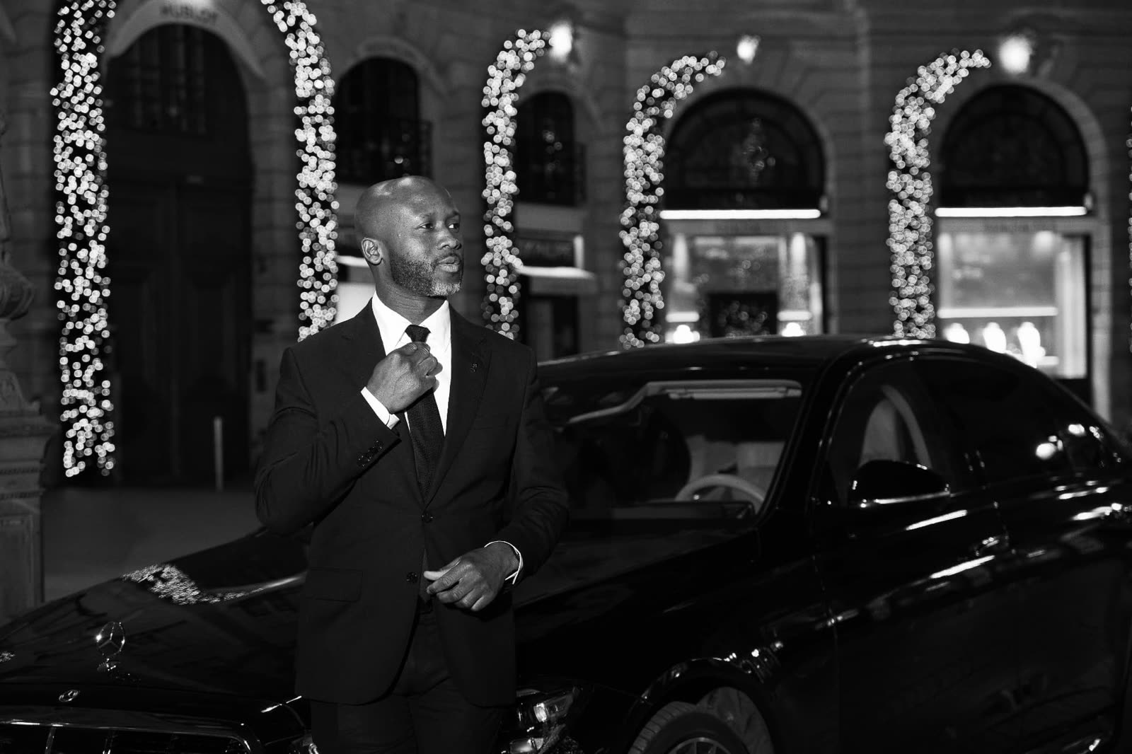 Portrait en noir et blanc d'Abdalah Sacko devant une Mercedes Classe S à Paris
